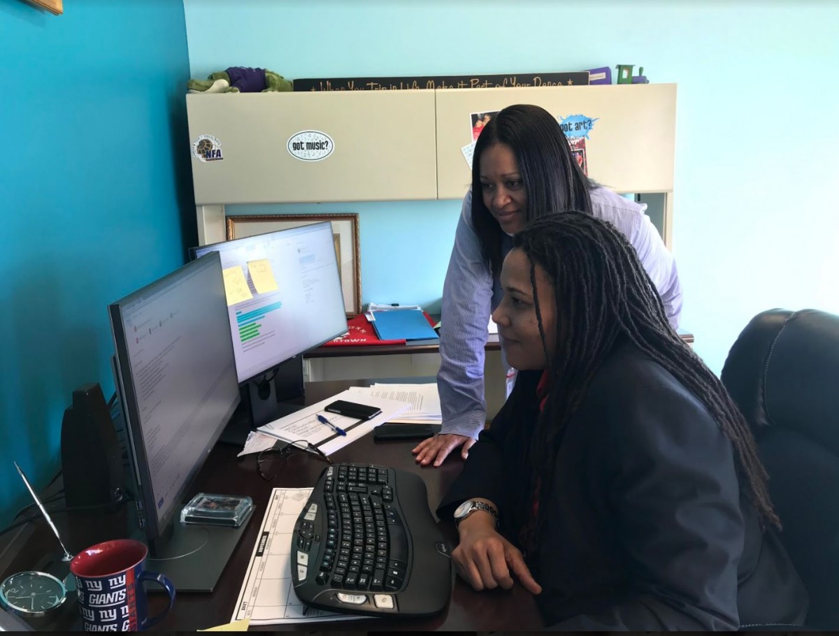 Photo 1 is of the NECSD Executive Director of Equity & Access, Dr. Ebony Green (seated at computer) with the NECSD Director of Family and Community Engagement, Pamela Peterson (standing) as they officially accept MBK Challenge.