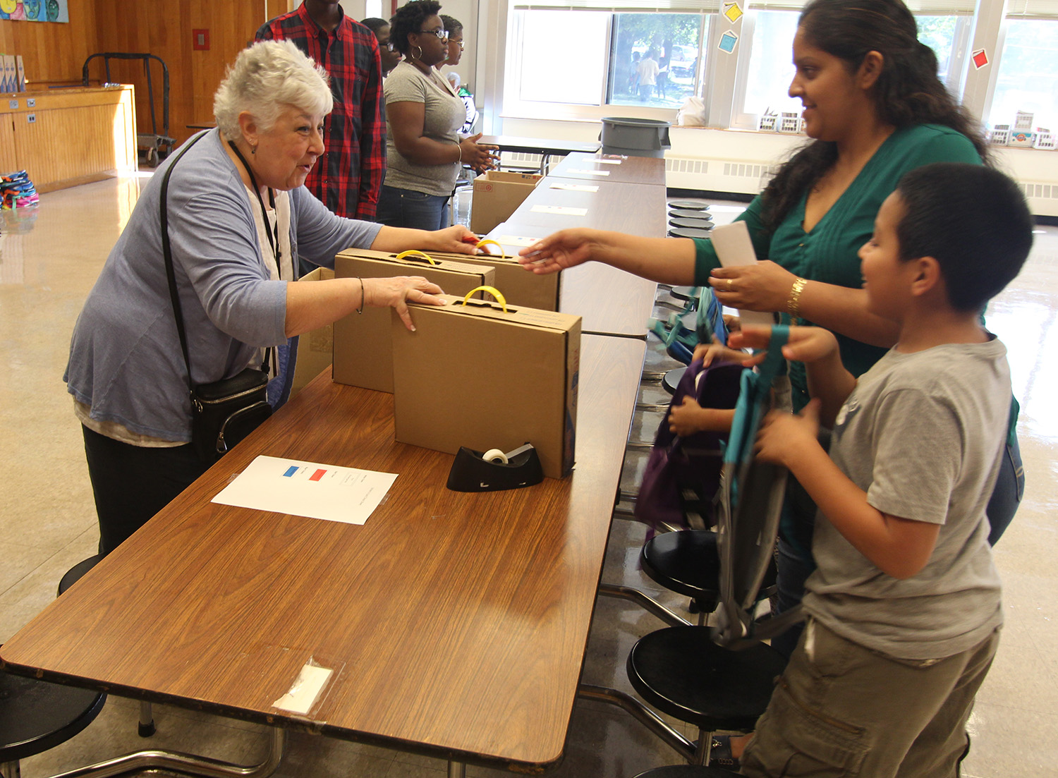 Board President Carole Mineo helps pass out backpacks to students.