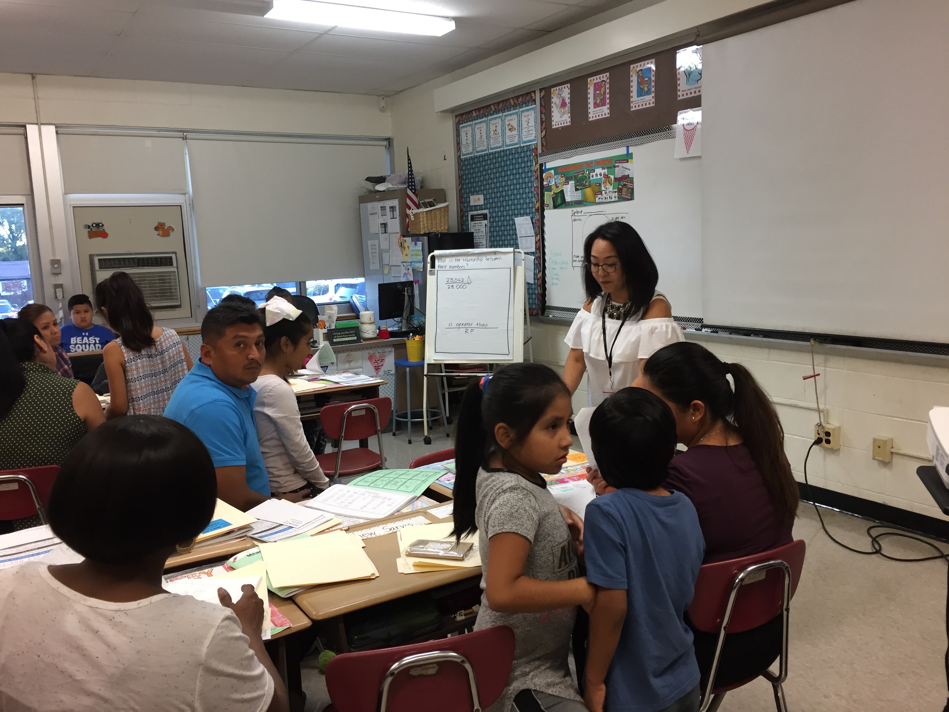 A teacher talking to students and families at open house