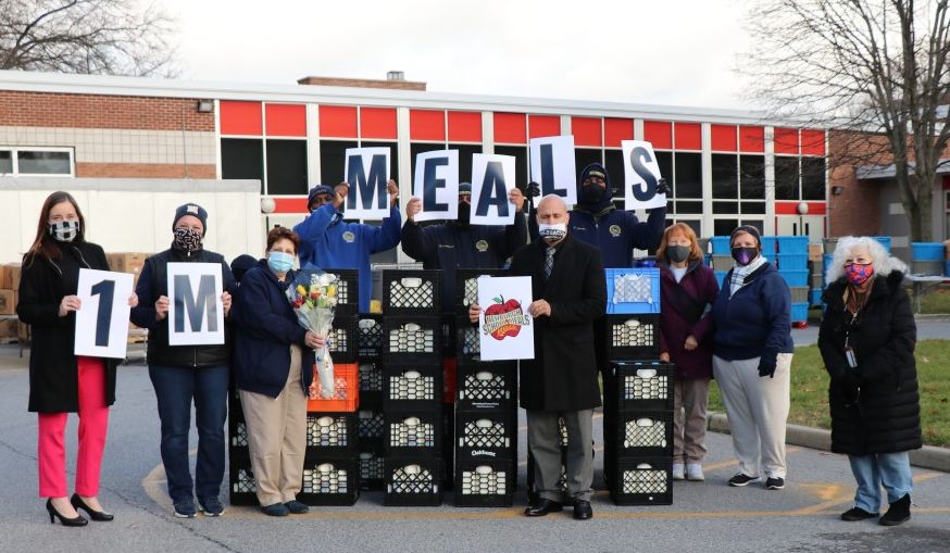 GAMS Meal Distribution team celebrates 1 Million Meals with signs and a group photo.