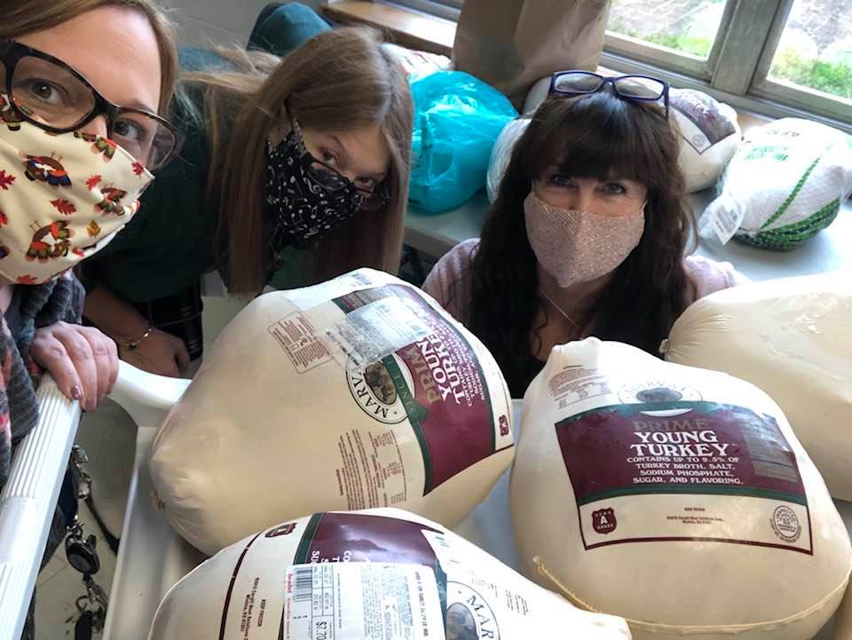 Faculty and staff pose for a photo near donated turkeys.