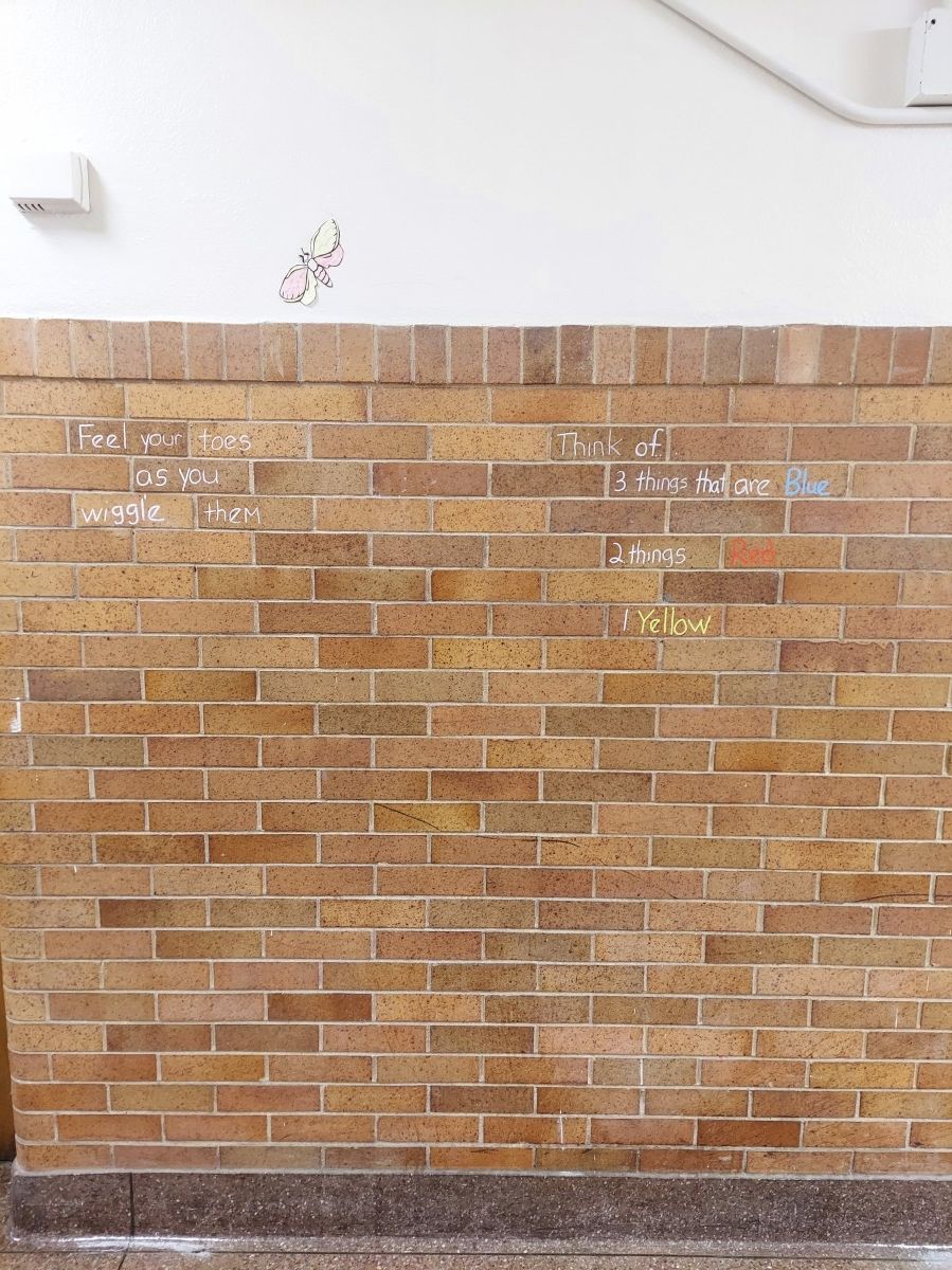 Brick wall with chalk writing by students and educators.