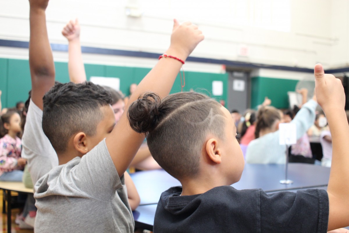 Students giving thumbs up at assembly