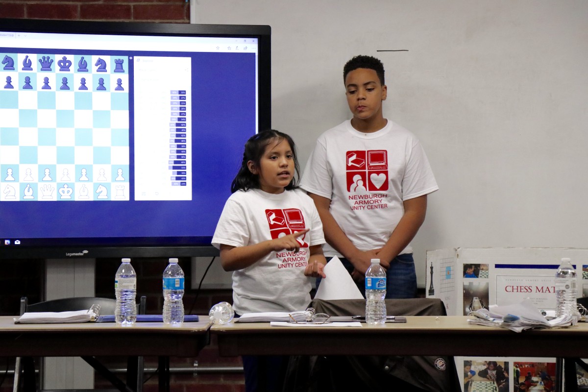 6th grader, Omari, explains the game of chess to Armory Board members