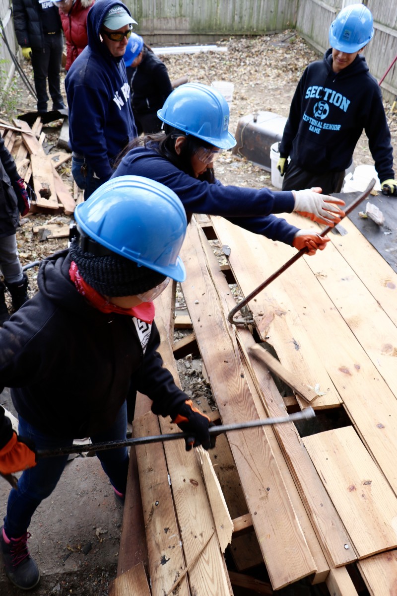 Students use crowbars to break up wood