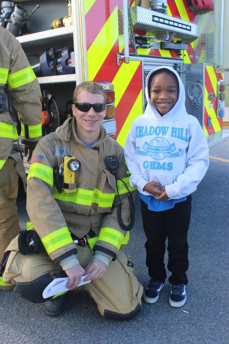 Student stands with a firefighter.