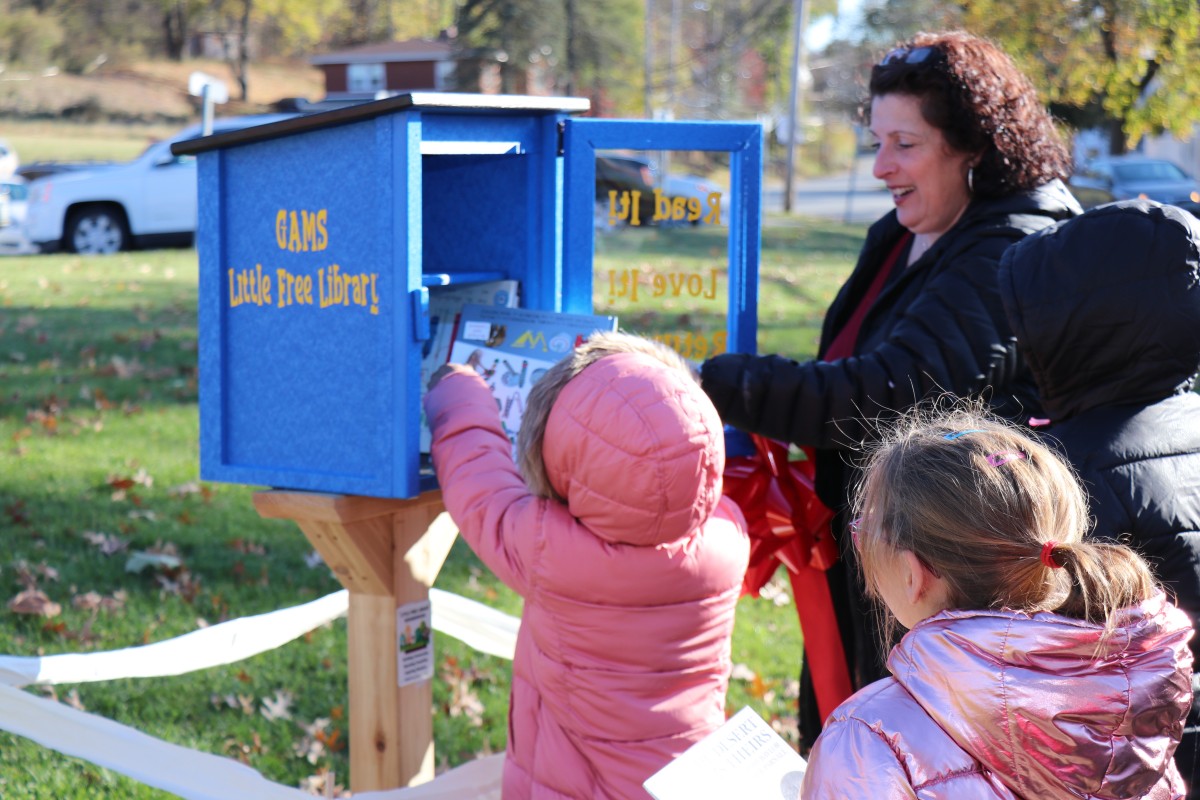 Students placing books in the outdoor lending library box.