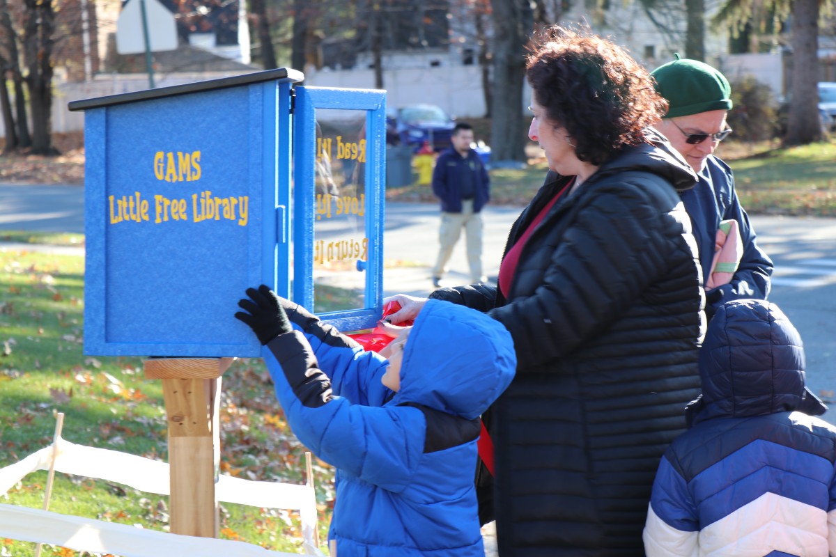 Students placing books in the outdoor lending library box.