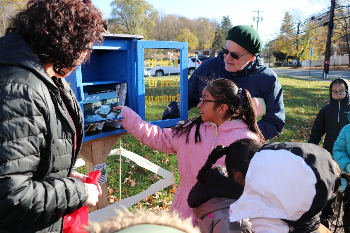 Students placing books in the outdoor lending library box.