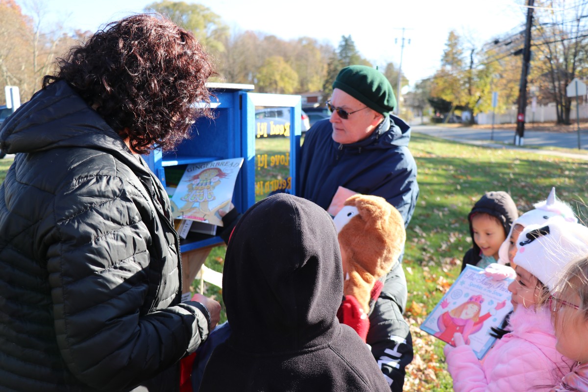 Students placing books in the outdoor lending library box.