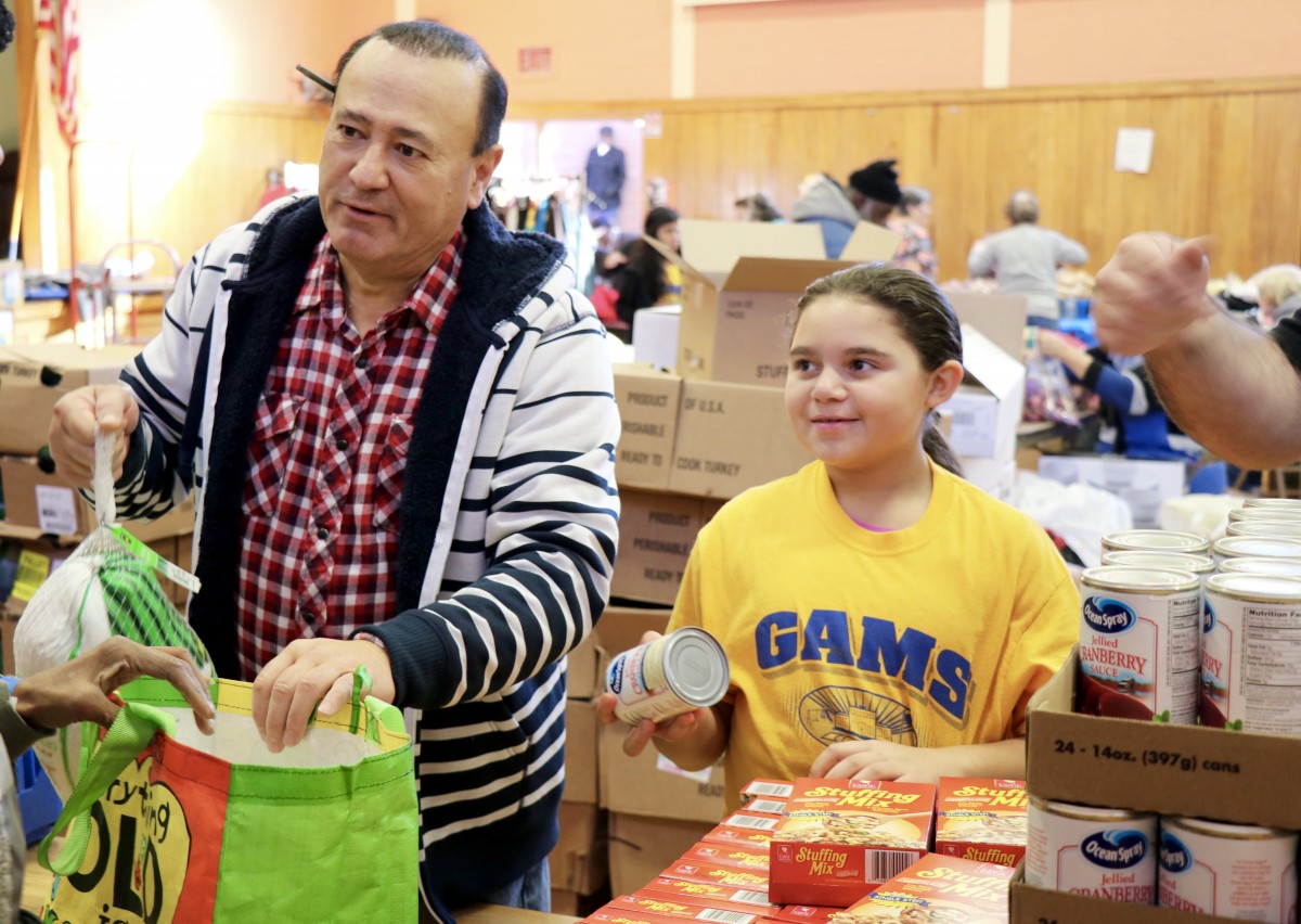 Student distributes food with Assemblyman Skartados