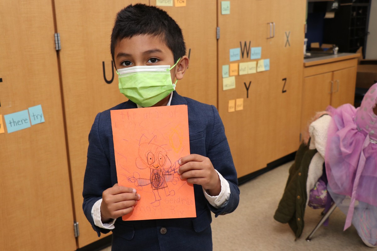 Scholar holding up the book that they wrote, illustrated, published, and read.