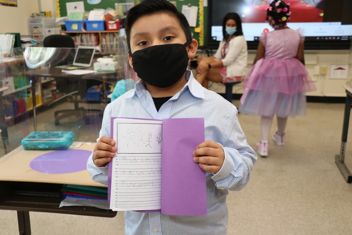 Scholar holding up the book that they wrote, illustrated, published, and read.