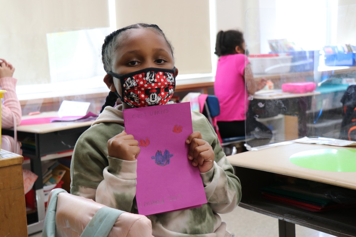 Scholar holding up the book that they wrote, illustrated, published, and read.