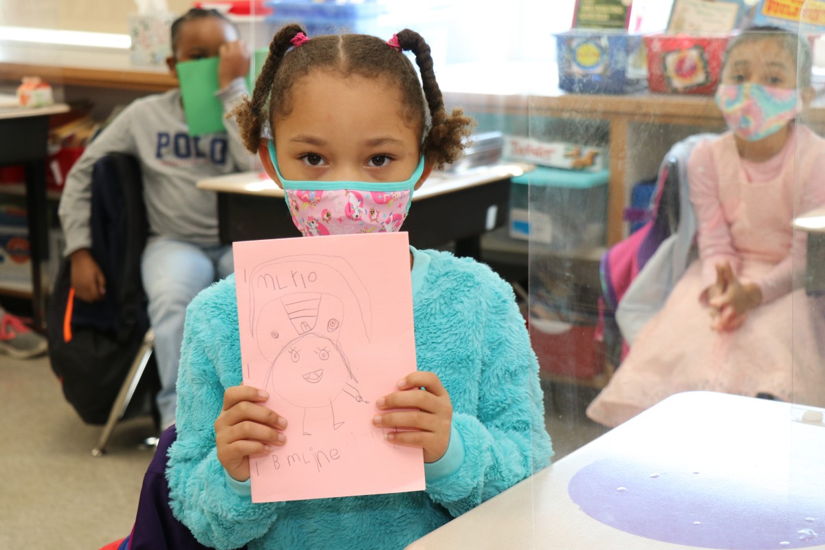 Scholar holding up the book that they wrote, illustrated, published, and read.