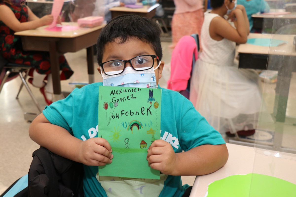 Scholar holding up the book that they wrote, illustrated, published, and read.