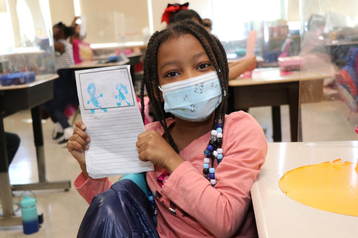 Scholar holding up the book that they wrote, illustrated, published, and read.