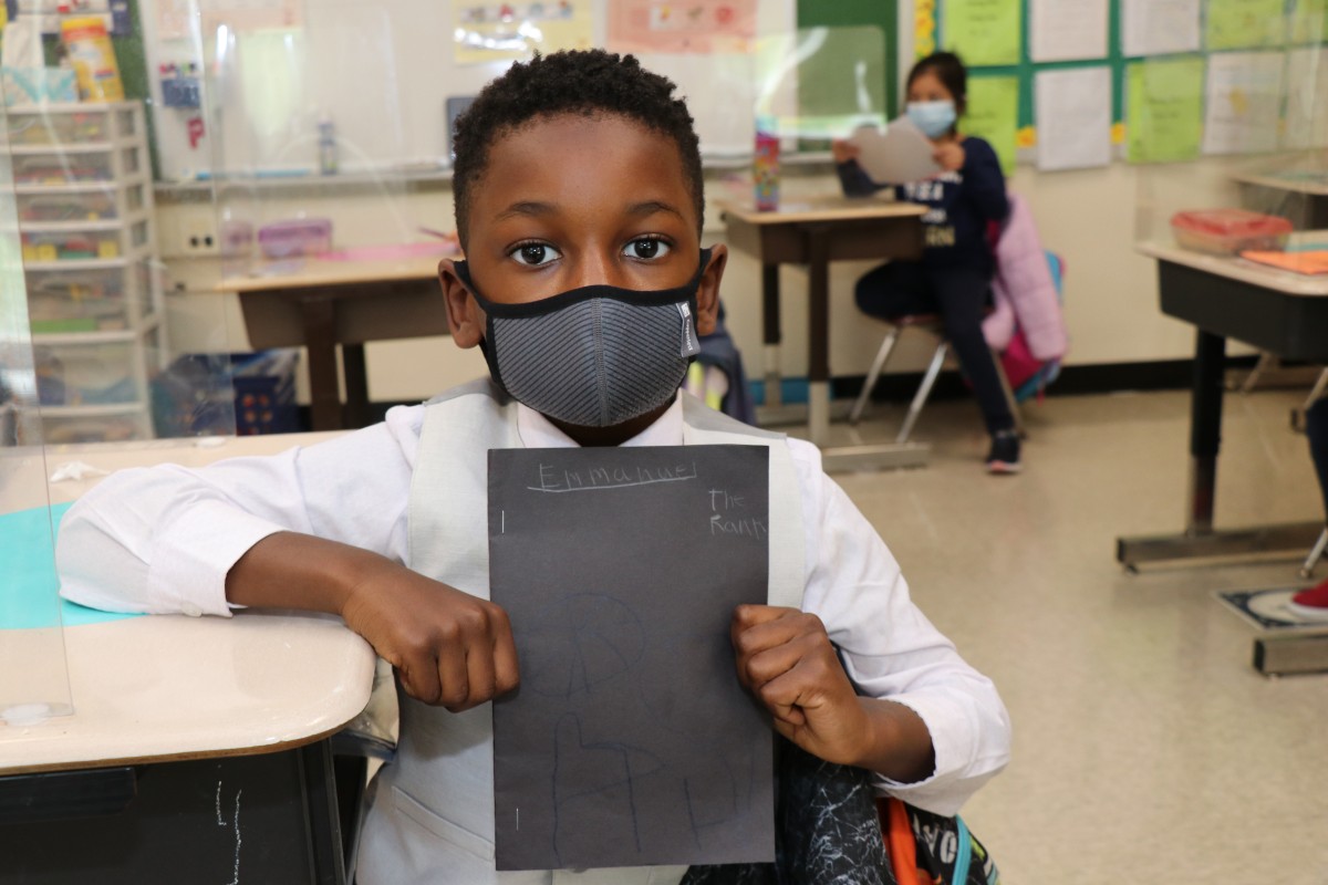 Scholar holding up the book that they wrote, illustrated, published, and read.