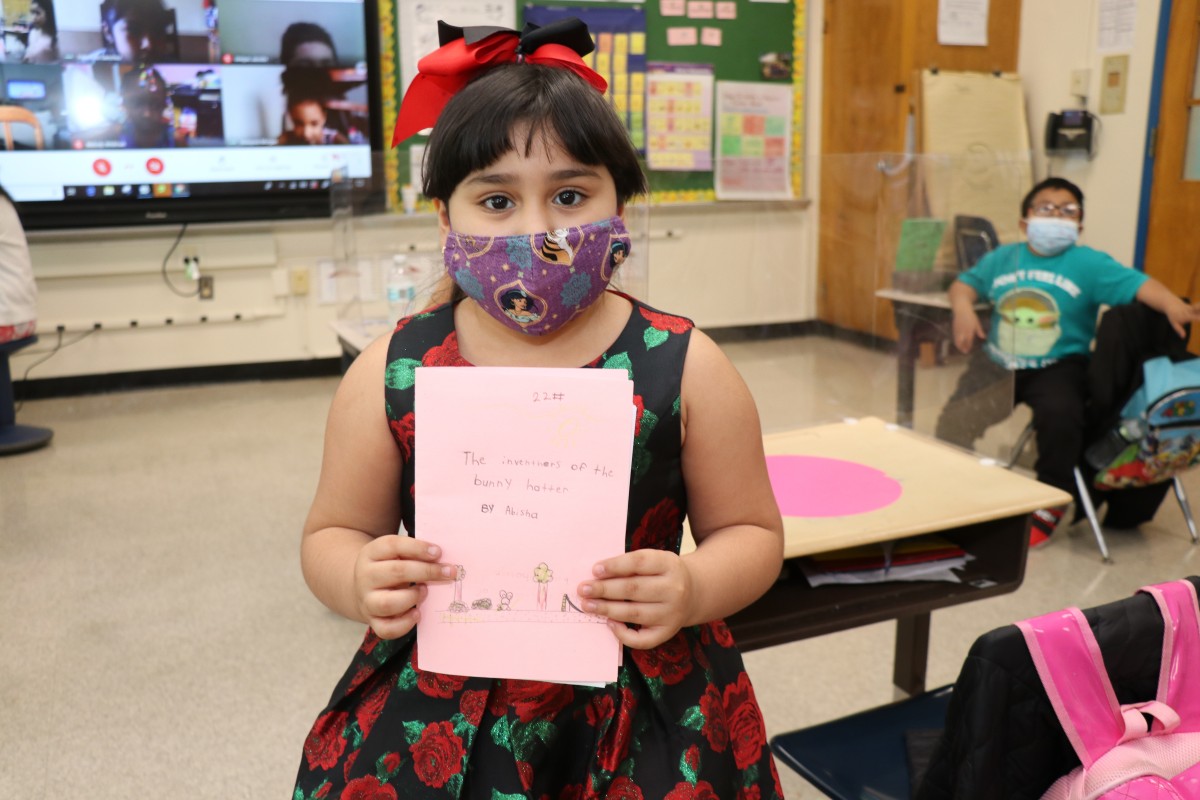 Scholar holding up the book that they wrote, illustrated, published, and read.