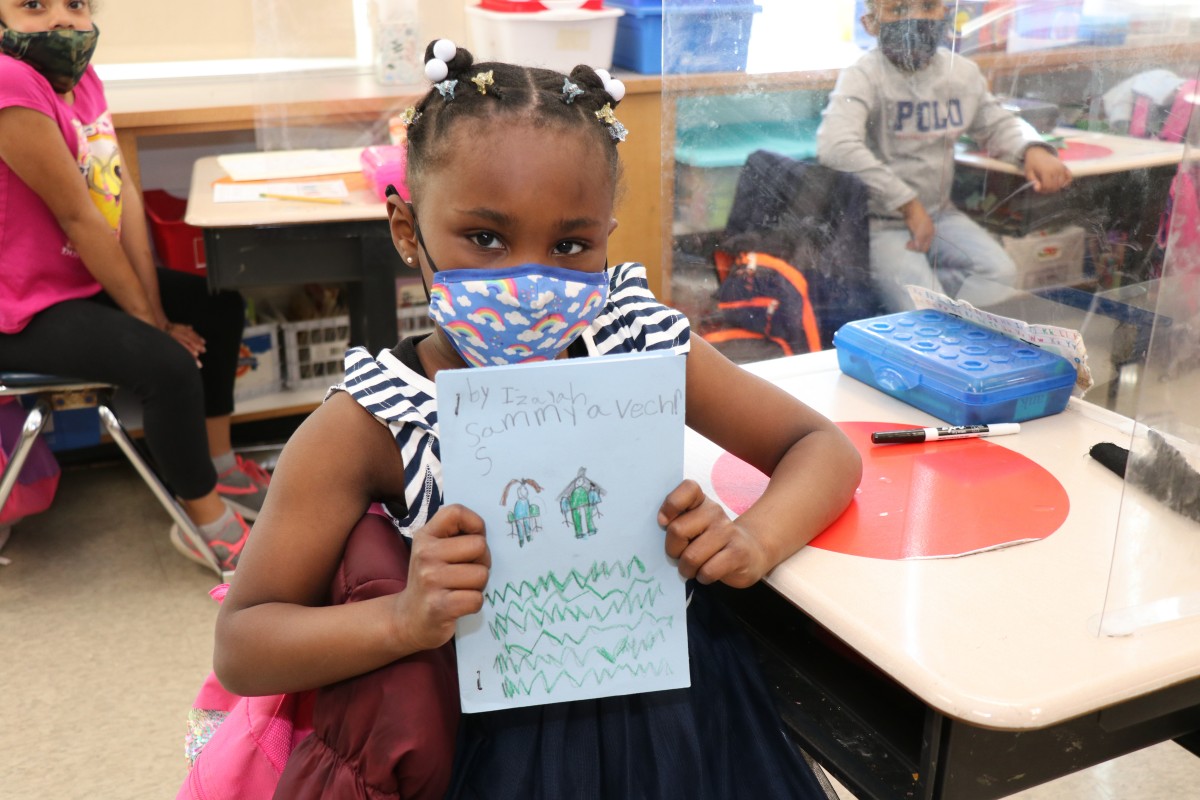 Scholar holding up the book that they wrote, illustrated, published, and read.
