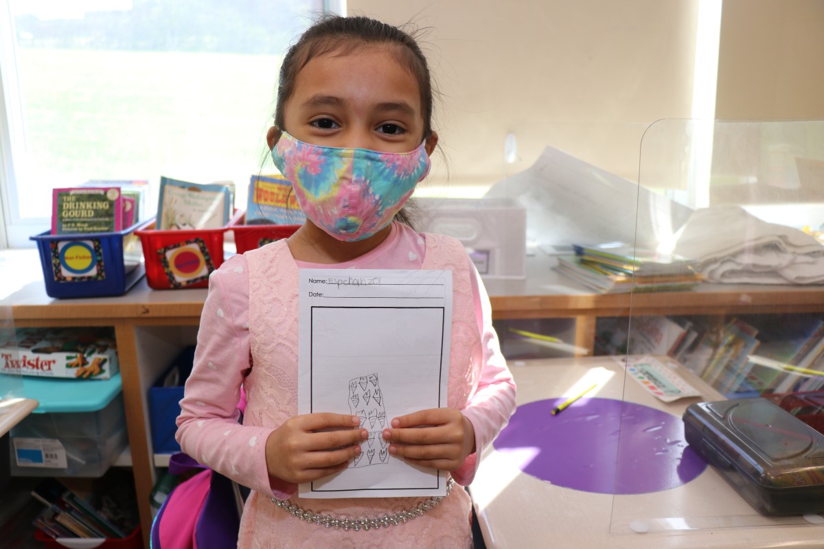 Scholar holding up the book that they wrote, illustrated, published, and read.