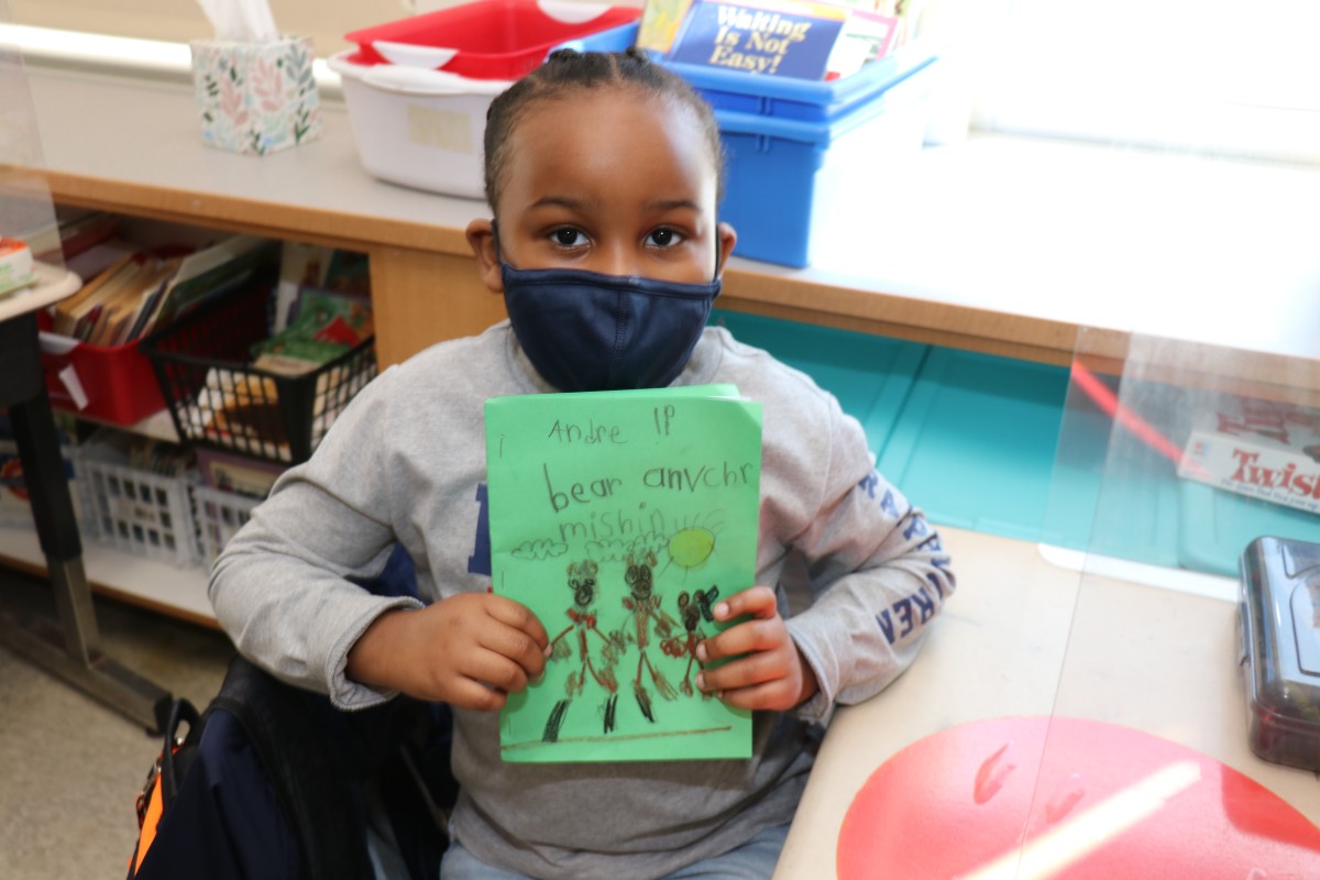 Scholar holding up the book that they wrote, illustrated, published, and read.