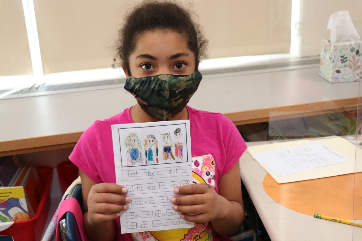 Scholar holding up the book that they wrote, illustrated, published, and read.