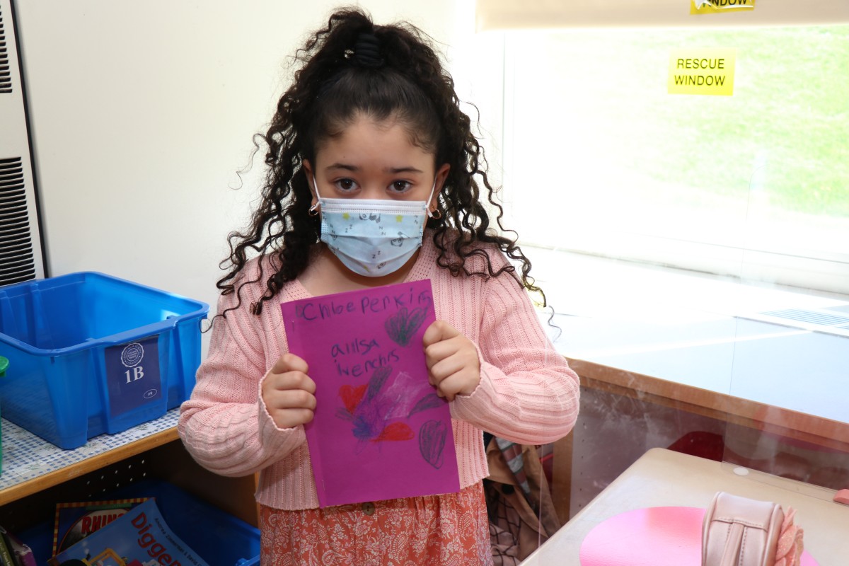 Scholar holding up the book that they wrote, illustrated, published, and read.