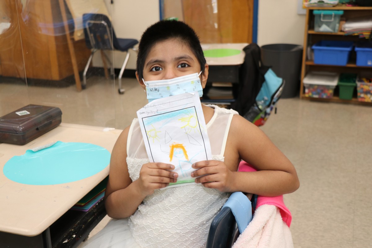 Scholar holding up the book that they wrote, illustrated, published, and read.
