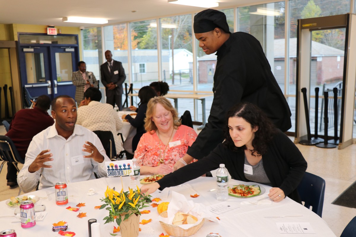 An NFA culinary scholar serves attendees their meal.