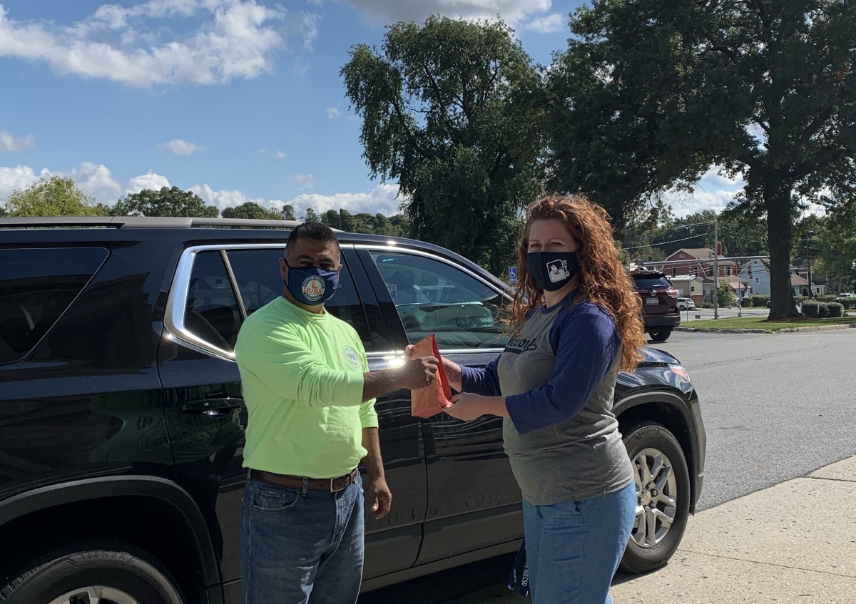 NFA Main librarian Ms. O'Neill delivers a book curbside for a scholar who is learning 100% virtually.