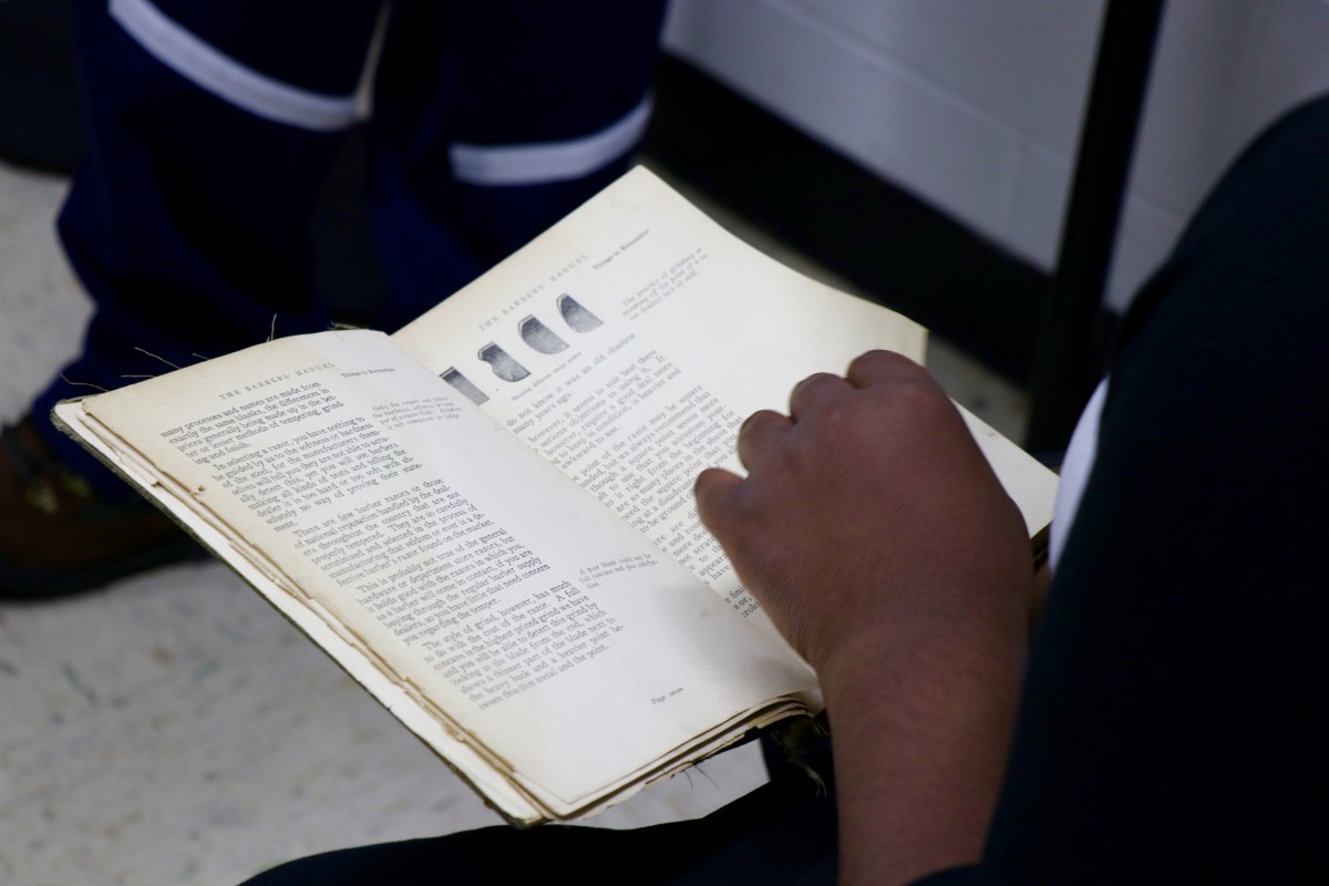 Students hold first barbering book from 1927