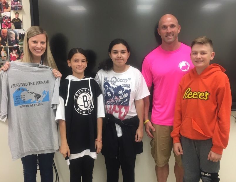 Students stand with Mr. Olsen and their t-shirt.