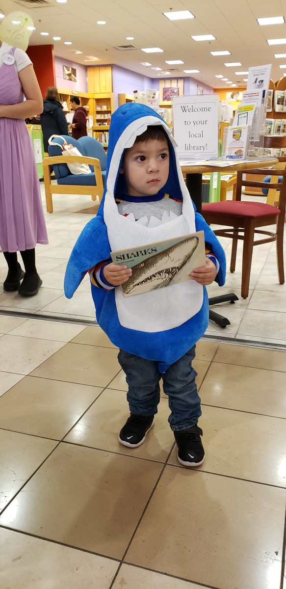 Child in costume holds a book.