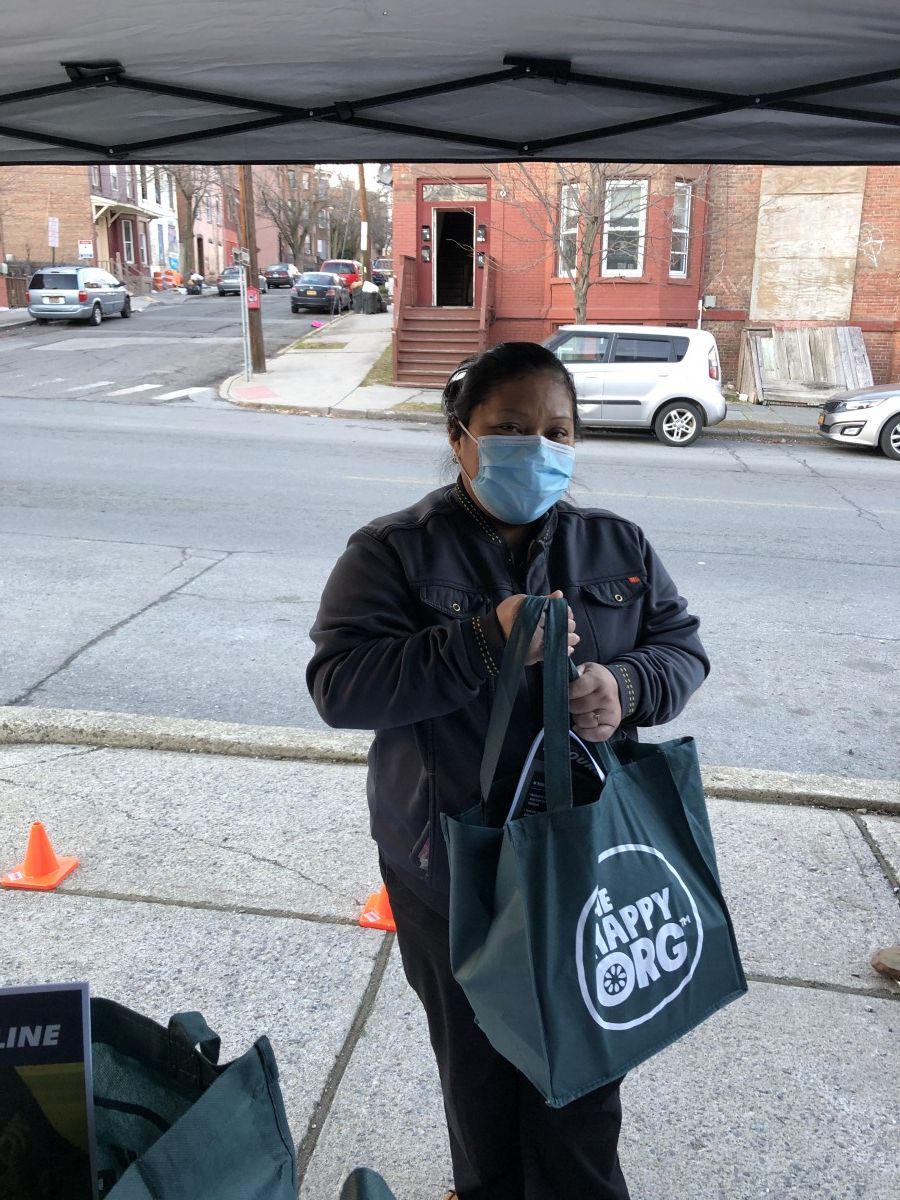 Community member poses for a photo holding their bag.