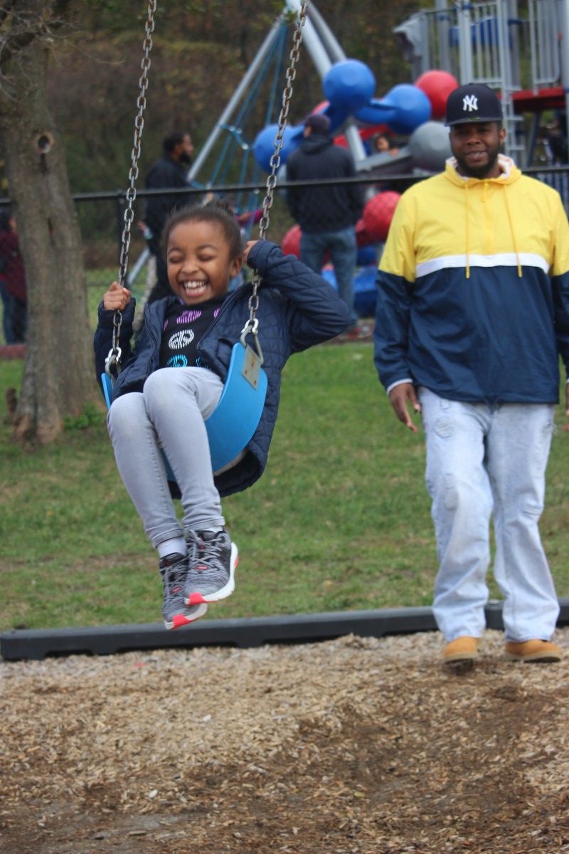 Father pushing child on a swing.