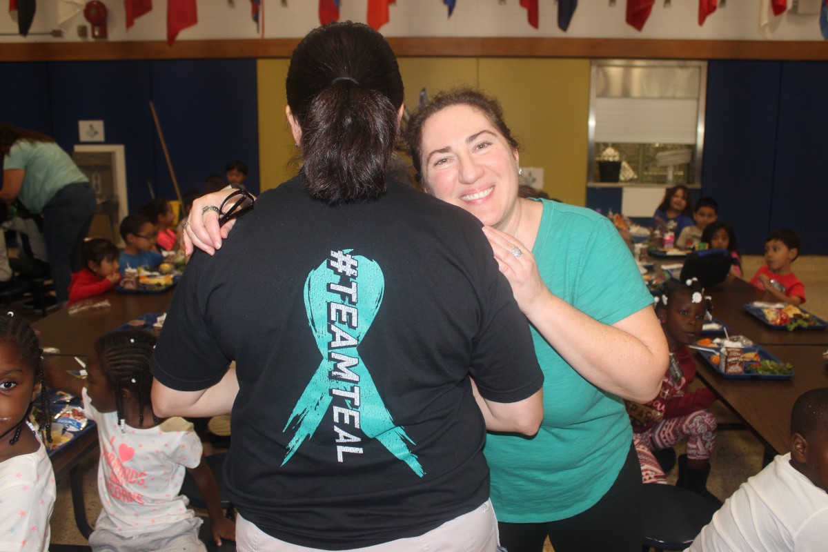 Participants pose for photo in teal.