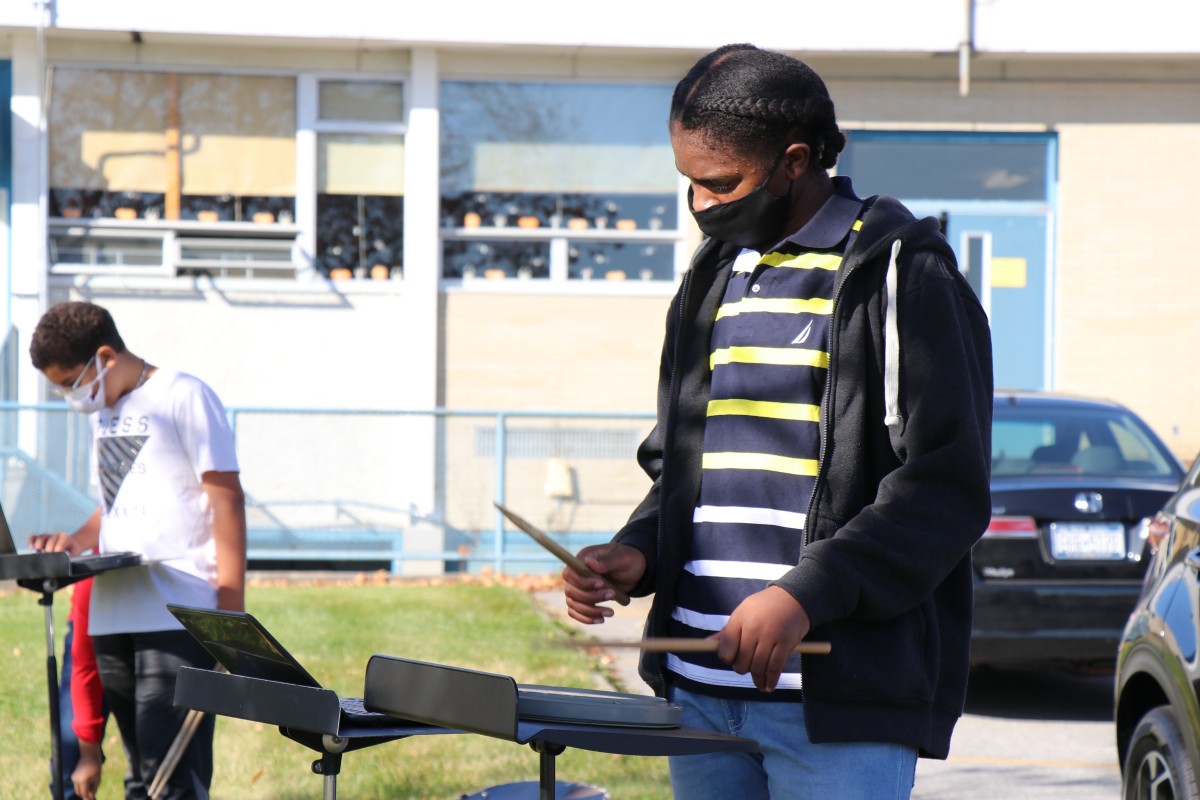 Student playing instrument outside.