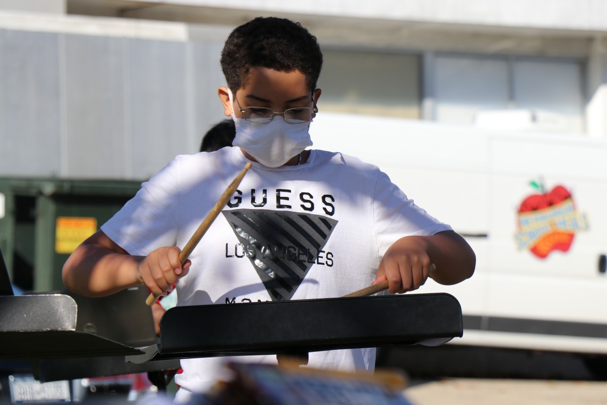 Student playing instrument outside.