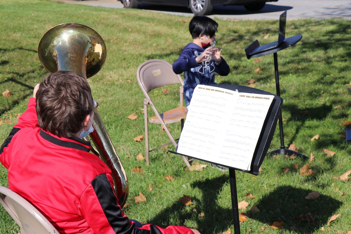 Student playing instrument outside.