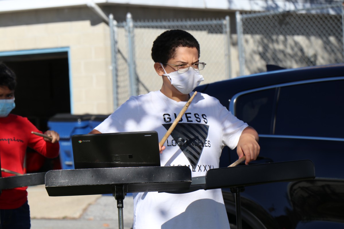 Student playing instrument outside.