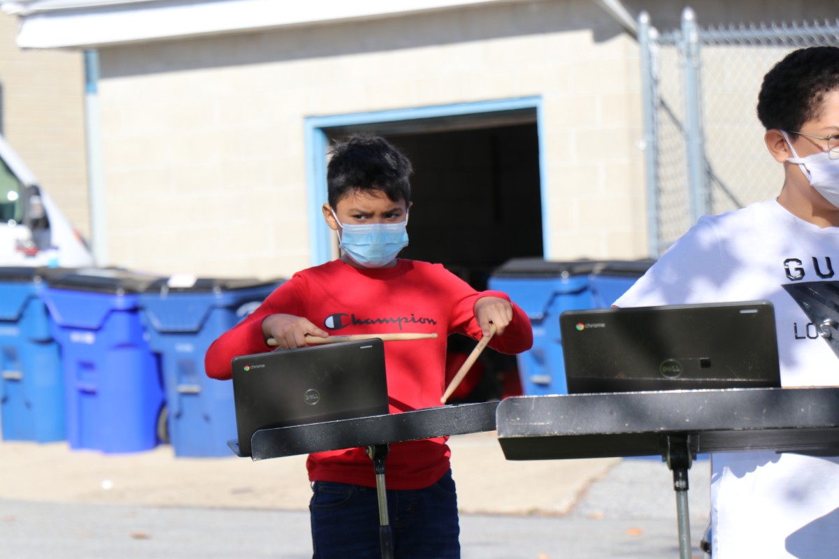 Student playing instrument outside.