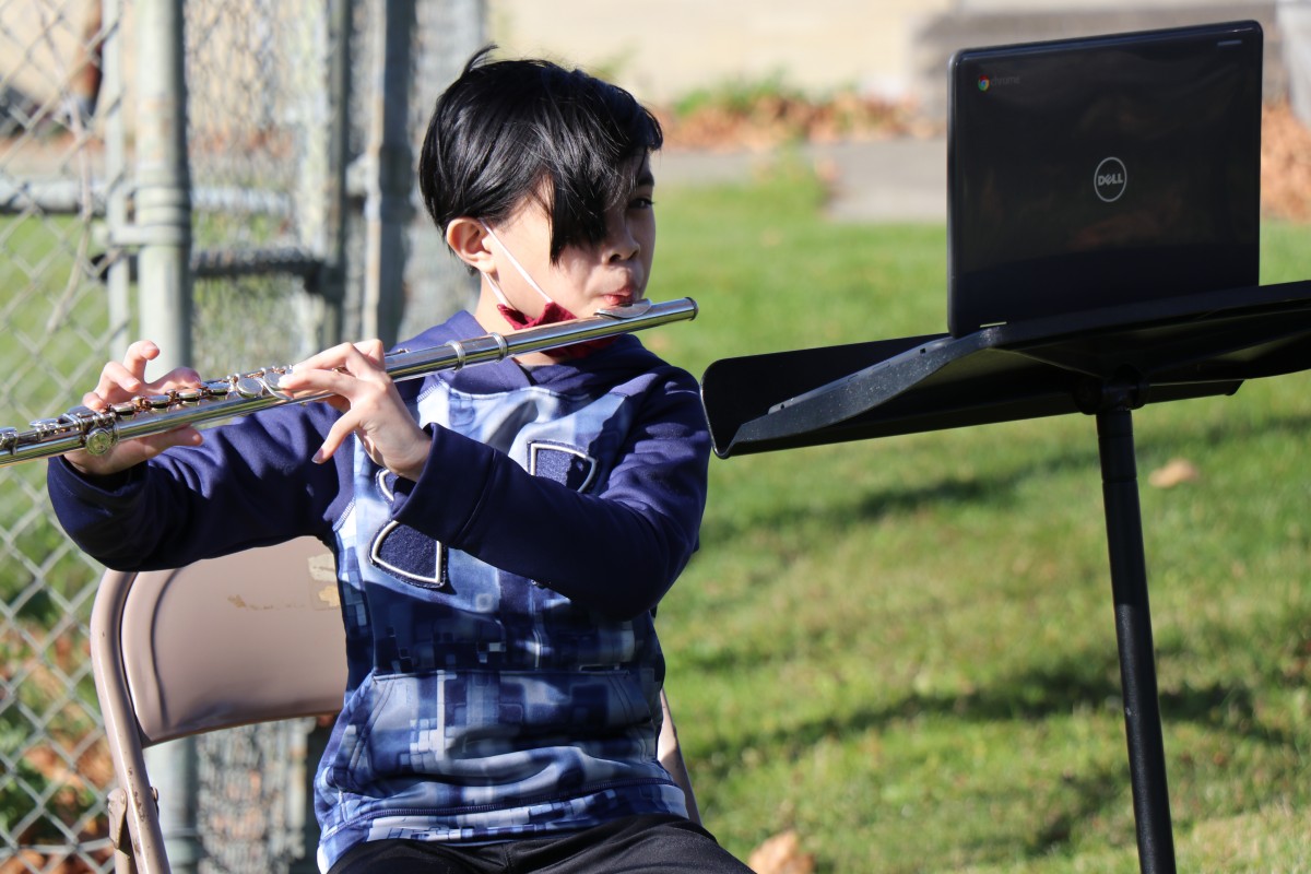 Student playing instrument outside.