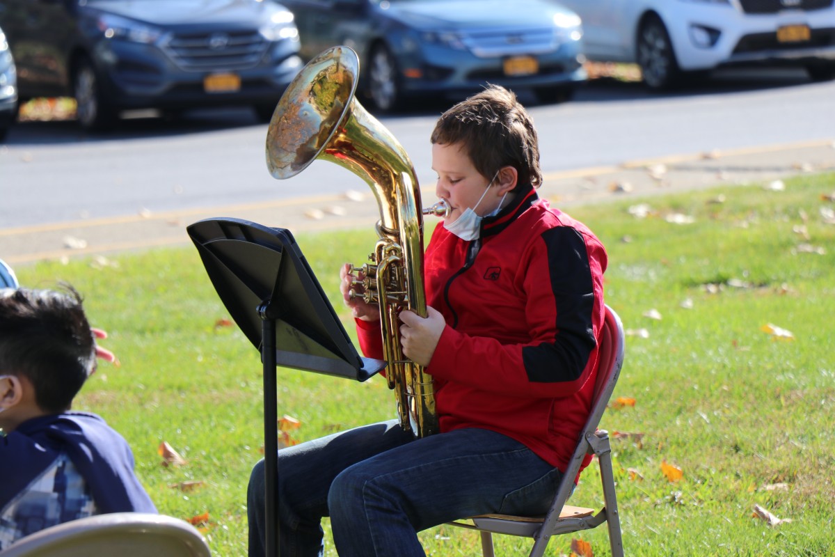 Student playing instrument outside.