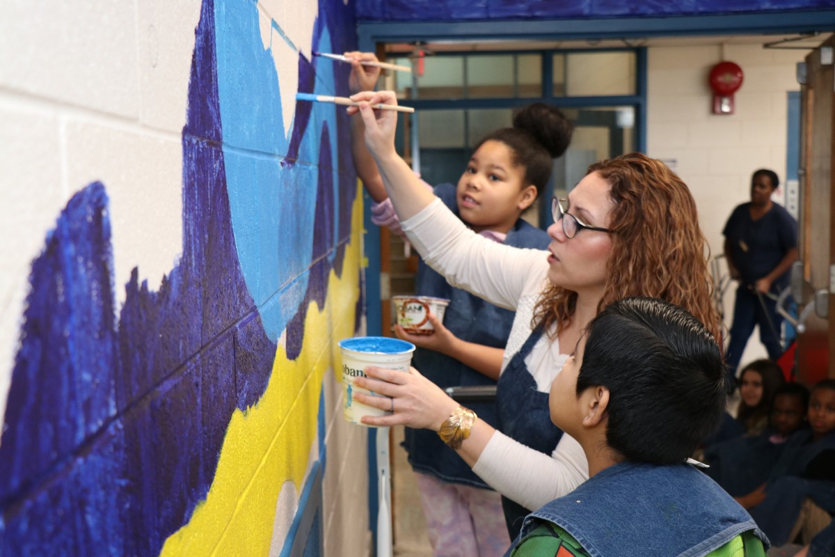 Teacher Mrs. Williams teaching students how to paint the mural.