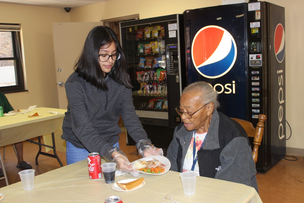 MHS volunteers handing out food and conversing with residents.