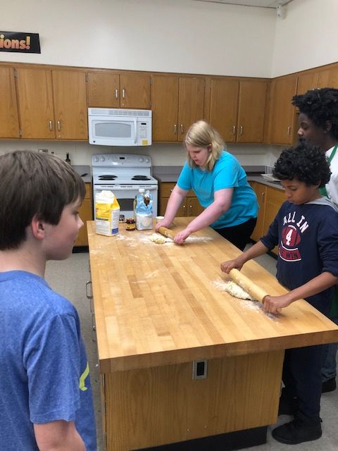 Student rolling pizza dough.