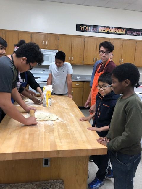 Student rolling pizza dough.