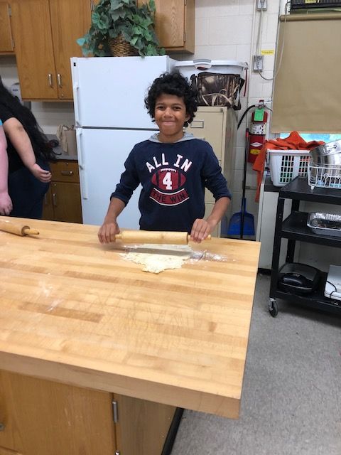 Student rolling pizza dough.