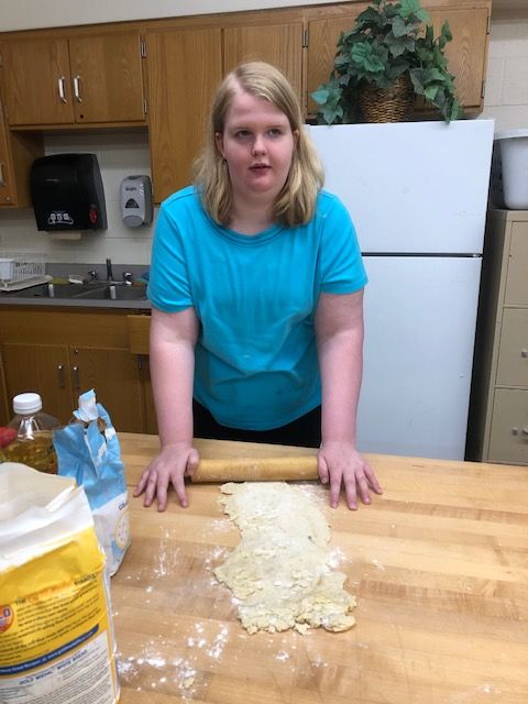 Student rolling pizza dough.